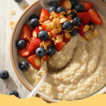 cremiges haferflocken porridge mit frischen beeren - Schüssel mit cremigem Haferflocken Porridge, reichlich belegt mit frischen Erdbeeren, Heidelbeeren und Himbeeren, mit einem Löffel bereit zum Essen.