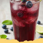 erfrischender beeren eistee mit minze und zitrone - Ein Glas erfrischender Beeren Eistee mit Minze und Zitrone auf einem Holztisch, garniert mit frischen Beeren und Minze.