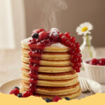 fluffige american pancakes mit beerenkompott perfektes muttertagsfruehstueck - Ein Stapel fluffiger American Pancakes mit reichlich frischem Beerenkompott und Ahornsirup, perfekt für das Muttertagsfrühstück.