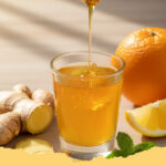 immun booster frischer ingwer zitronen shot mit honig - Frischer Ingwer-Zitronen-Shot mit Honig in kleinen Gläsern, verziert mit Ingwerscheiben und Zitronenspalten