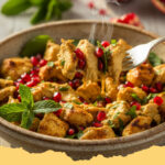 orientalischer haehnchen salat mit granatapfel und minze - Ein bunter, frischer orientalischer Hähnchensalat mit leuchtend roten Granatapfelkernen und grüner Minze in einer großen Schüssel.