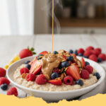 proteinhafte power haferflocken mit beeren und mandelbutter - Schüssel mit proteinhaften Power Haferflocken, garniert mit frischen Beeren und Mandelbutter-Swirls, auf einem Holztisch mit Löffel.