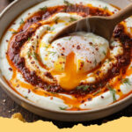 tuerkische eier cilbir mit joghurt und paprikabutter - Zwei Teller mit Türkische Eier Çılbır mit Joghurt und Paprikabutter, garniert mit frischer Minze und Brot.