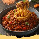 vegane bolognese aus roten linsen - Schüssel mit herzhafter veganer Bolognese aus roten Linsen und frischem Basilikum auf Pasta