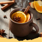 warmer apfel zimt punsch alkoholfrei - Ein dampfender Becher mit warmem Apfel-Zimt-Punsch, garniert mit Apfelscheiben und Zimtstangen, auf einem Holztisch mit Herbstdekoration.