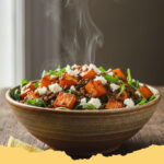 warmer linsensalat mit suesskartoffel und feta - Ein appetitlicher, warmer Linsensalat mit gerösteten Süßkartoffeln, Feta-Käse und frischen Kräutern in einer Servierschale.