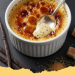 klassisches creme brulee ohne alkohol - Ein goldbraun karamellisiertes klassisches Crème brûlée ohne Alkohol in einer kleinen weißen Schale, serviert mit frischen Himbeeren.
