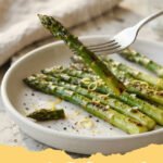 rezepte mit grünen spargel - Gebratener grüner Spargel mit Knoblauch und Zitrone auf einem Teller, garniert mit frischen Kräutern.